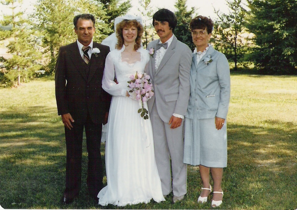 Shauna and Richard LeBlanc on their wedding day in 1981, standing outdoors with family